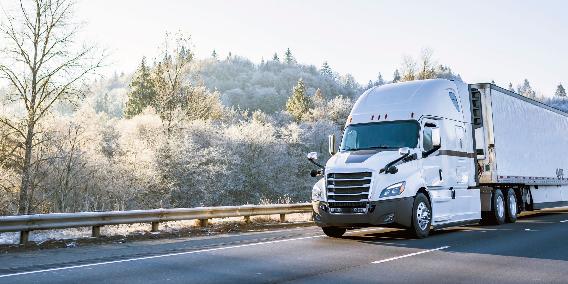 A white refrigerated truck hauling cold freight on a frosty winter morning
