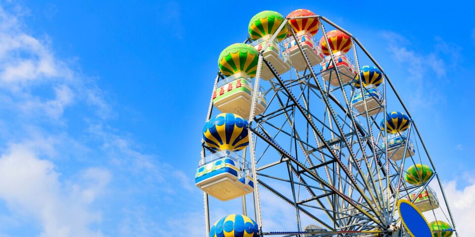 A colorful amusement park ferris wheel against a blue sky