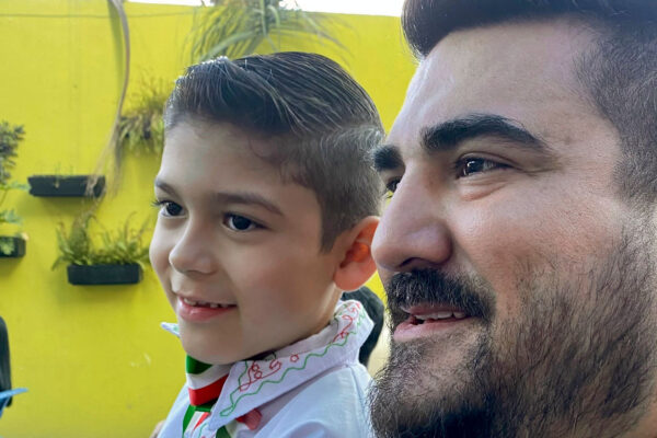 US Mexico cross border logistics specialist, Horacio De La Garza, seated next to his son, who is wearing white shirt with red and green embroidery