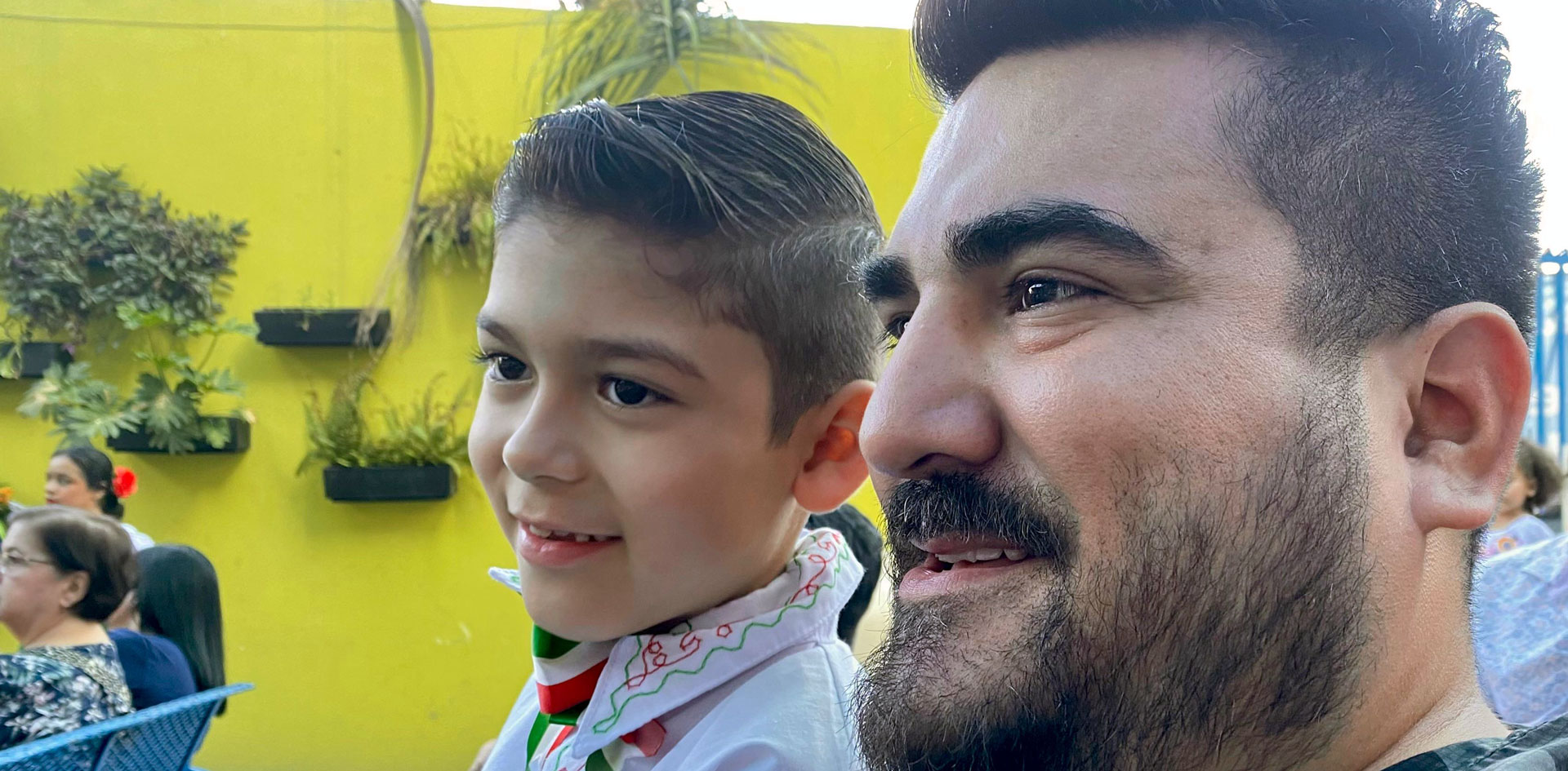 US Mexico cross border logistics specialist, Horacio De La Garza, seated next to his son, who is wearing white shirt with red and green embroidery